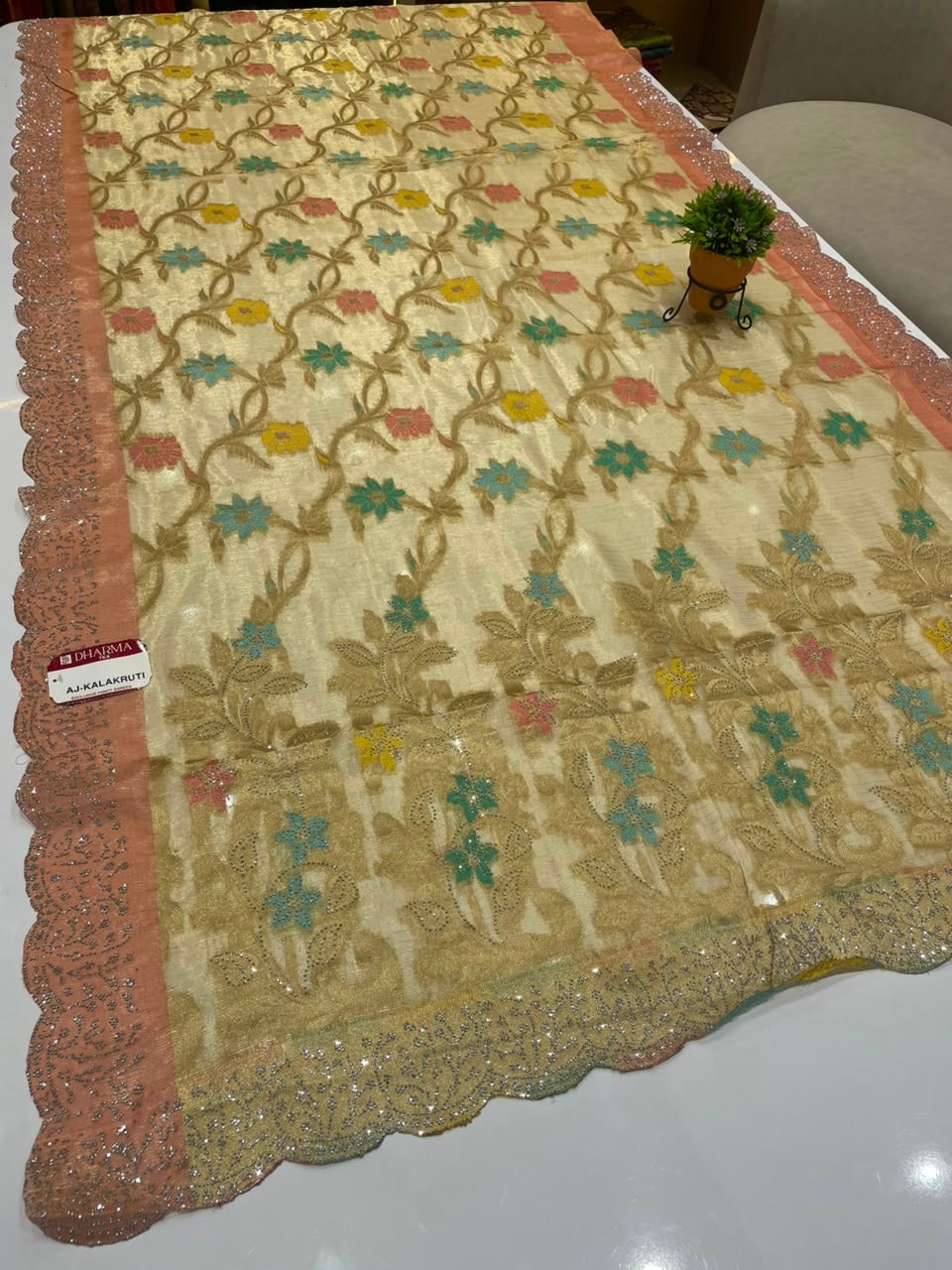 AJ-KALAKRUTI-CATLOGUE A STUNNING FANCY FABRIC SAREE FEATURING RICH MULTI-COLOUR WEAVING, HEAVY SCALLOPED CUTWORK BORDER WITH PREMIUM SIROSKI WORK, AND A BEAUTIFULLY DESIGNED MULTI-COLOUR RICH PALLU, PAIRED WITH A MATCHING BLOUSE PIECE